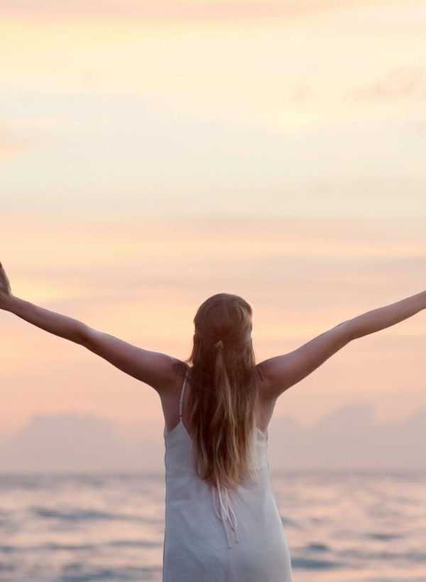 A woman enjoying a serene sunset on Unawatuna Beach, Sri Lanka, depicting peace and freedom.