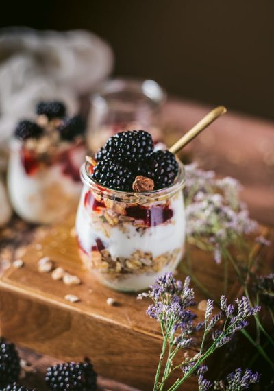Delicious blackberry and yogurt parfait with granola served in jars and decorated with flowers.